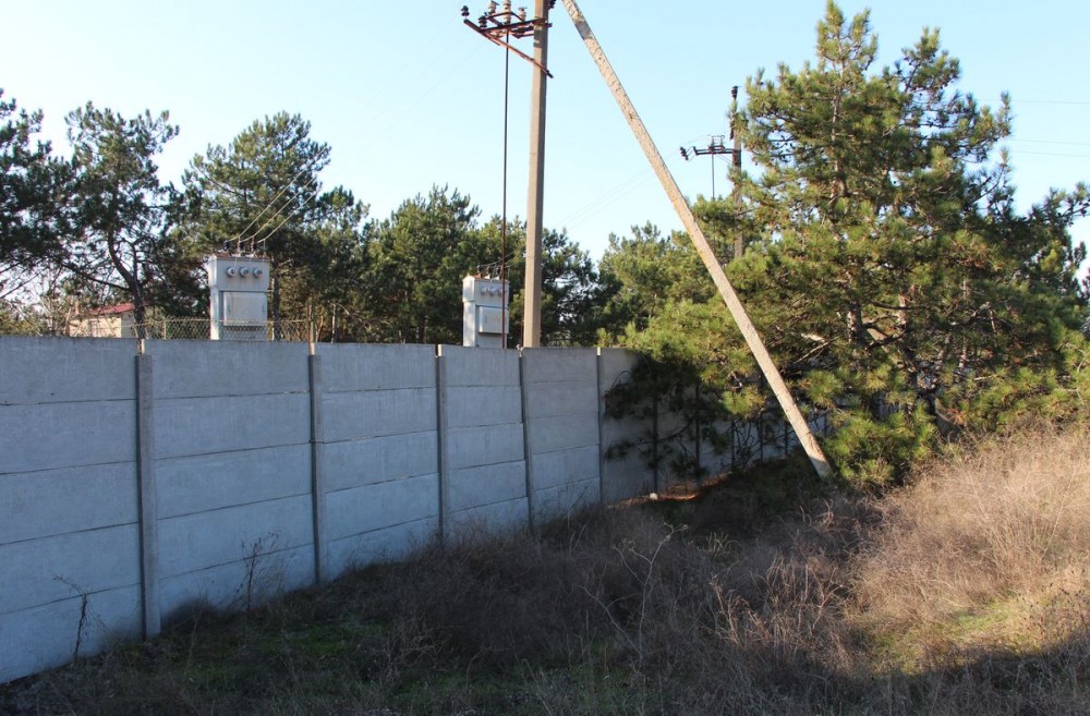 Високий паркан огороджує територію Соснового Бору