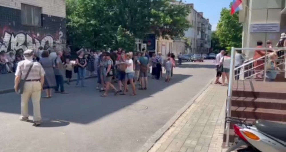 Херсонцы, желающие получить оккупантский паспорт, вынуждены искать спасения в тени дома, расположенного напротив "паспортного сервиса".